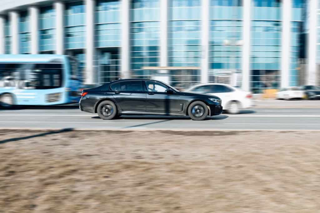 Motor Hills | 15 Reasons Why Luxury Cars Are So Expensive A black 2022 BMW 7-Series G12 745Le driving on the road with blurred background