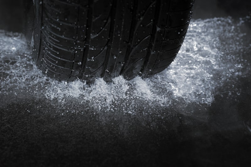 Motor Hills | Is It Worth Buying Expensive Tires? How to Decide Close up of a car tire driving on a wet road with the groove marks visible on the tread