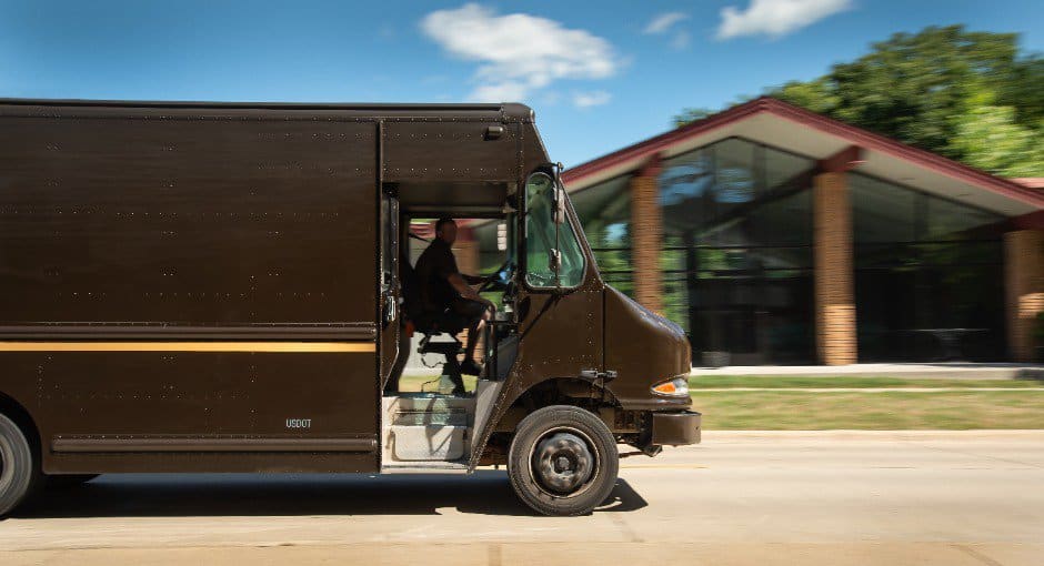 UPS delivery driver in motion with background blurred in urban streets