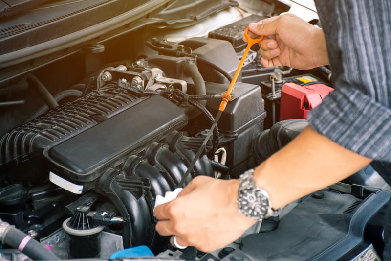 Motor Hills | How To Care Of Your Car When You're In The Military Man checking the oil level and performing regular routine maintenance on the vehicle